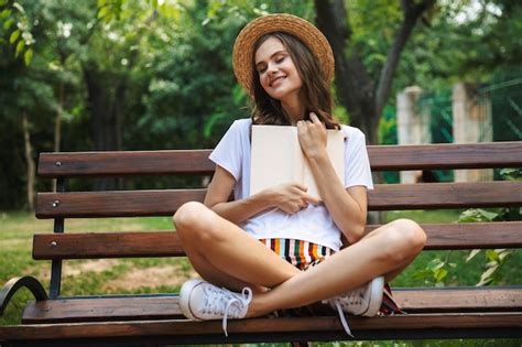 Premium Photo Delighted Young Girl Reading A Book While Sitting At