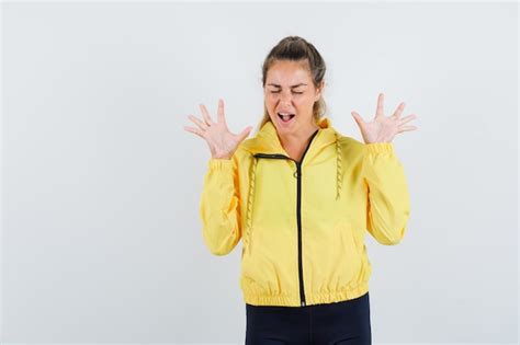 Femme Blonde En Blouson Aviateur Jaune Et Pantalon Noir Levant Les