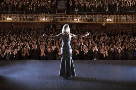 Performer Standing With Arms Outstretched On Stage In Theater Stock Photo