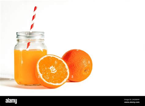 Glass Jar With A Tube With Freshly Squeezed Orange Juice Stands On A White Background Next To