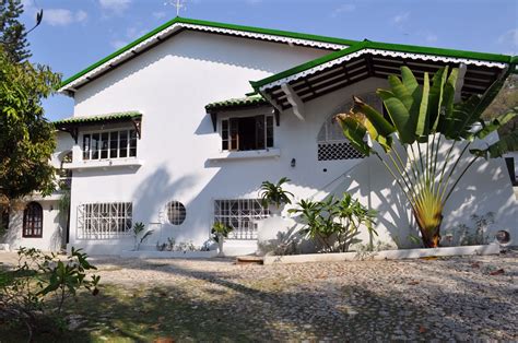 A White House With Green Roof And Windows