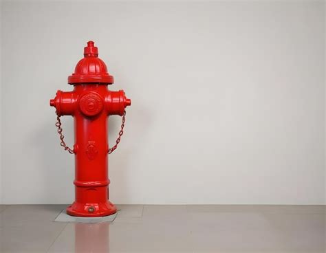 Premium Photo A Red Fire Hydrant On A Floor With A Plain Wall In The