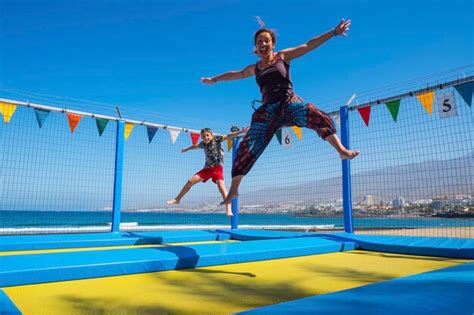 Premium Photo Cheerful Woman Jumping With Son On Trampoline Against