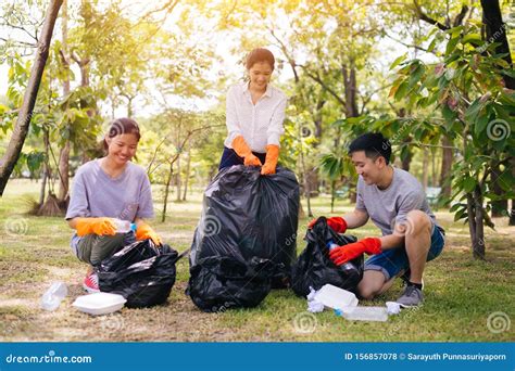 Young Asian People Collecting Trash In Garbage Bag In The Park Stock