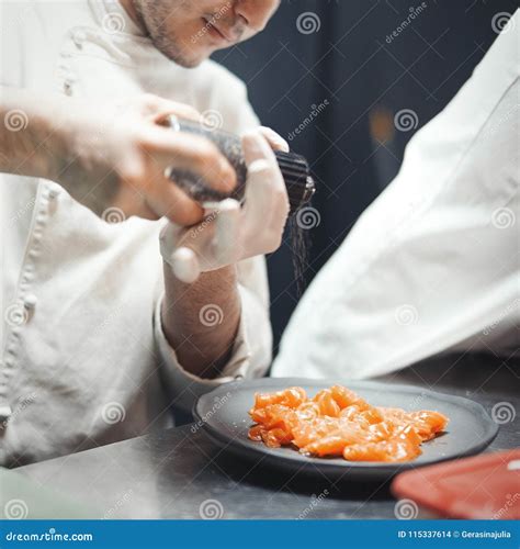 Restaurant Chef Cook Preparing Salmon Filet And Peppering It Stock