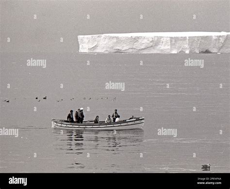 HMS Endurance sea boat and sailors passing a massive iceberg on a trip ...