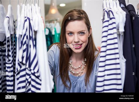 Brunette Smiling Through Clothes Rail Stock Photo Alamy