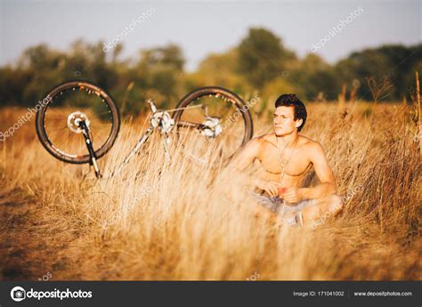 A Handsome Muscular Guy With A Naked Torso Sitting Near A Bicycle In