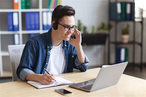 Young Male Office Employee Wearing Headset Watching Online Webinar At