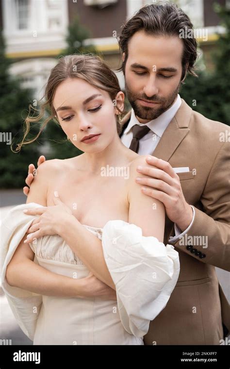 Bearded Groom In Formal Wear Hugging Pretty Bride In White Dress Stock