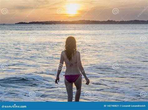 Beautiful Woman In Pink Bikini Standing In The Water On The Beach