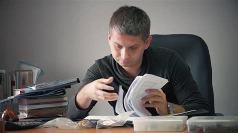 Happy young businessman sitting in office with business papers on table ...