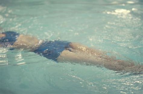 A Woman Swimming In A Pool With Her Head Above The Water As She Swims