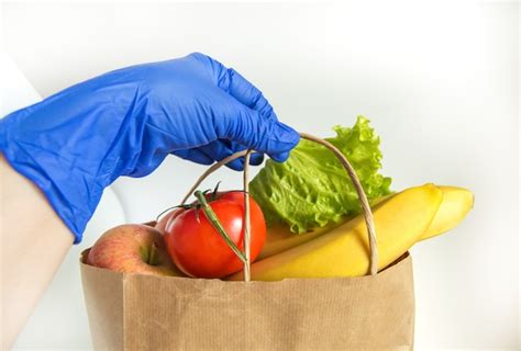 Una Mano En Un Guante De Goma Sostiene Una Bolsa De Papel Con Verduras