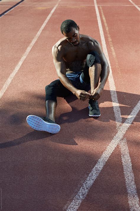 Black Athlete Tying His Shoes In The Track And Field Del Colaborador