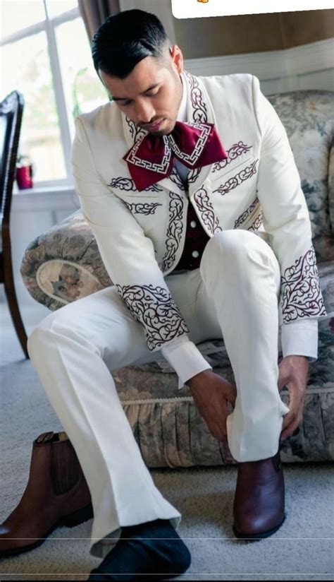 A Man In A White Suit And Red Tie Sitting On A Chair With His Foot Up