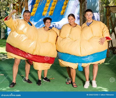 Group Photo Of Smiling Men And Women Wearing Funny Sumo Suits Stock