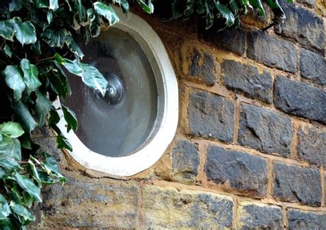 Una Ventana Redonda En Una Pared De Ladrillos Con Hojas Verdes Foto