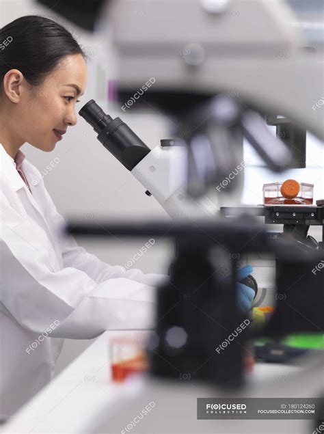 Female Scientist Examining Cell Cultures Growing In A Culture Jar By