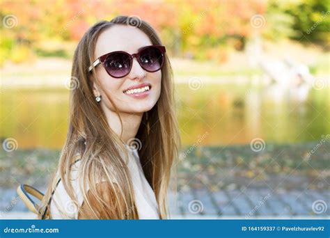 Beautiful Happy Girl In Sunglasses Smiling On A Park Background Close