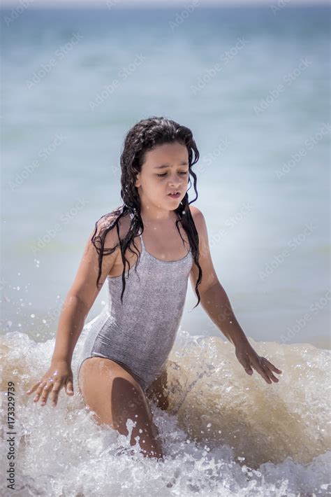 Niña morena bañándose en el mar y jugando con las olas foto de Stock