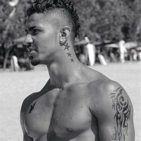 A Shirtless Man With Tattoos On His Face And Chest Standing In Front Of