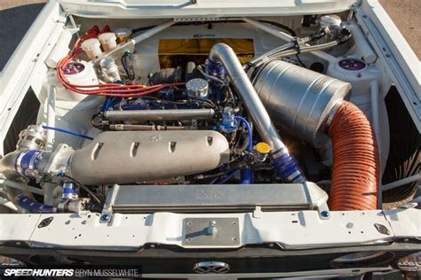 The Engine Compartment Of A Car With Its Hood Up And Hoses Running