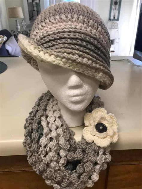 A Crocheted Hat Scarf And Flower On A Mannequin S Head