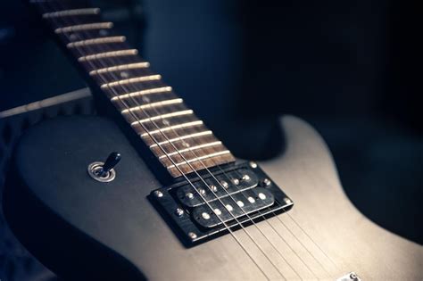 Closeup guitarra eléctrica negra sobre un fondo oscuro Foto Gratis