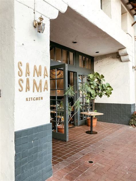 The Outside Of A Restaurant With Potted Plants On The Patio And Signage