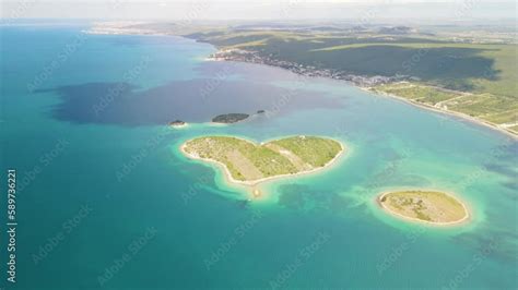 Aerial and cinematic view of a heart-shaped island nestled in the pristine waters of Croatia ...