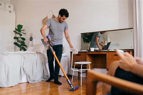 Full Length Of Man Cleaning Bedroom With Vacuum Cleaner Stock Photo