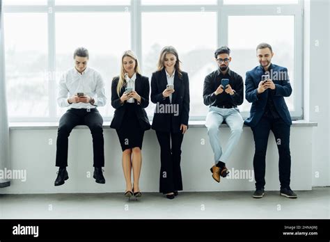 Group Of Business People Using Mobile Phones And Sitting On Couch