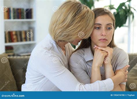 Middle Aged Mother And Daughter Talking On Sofa In Living Room Stock