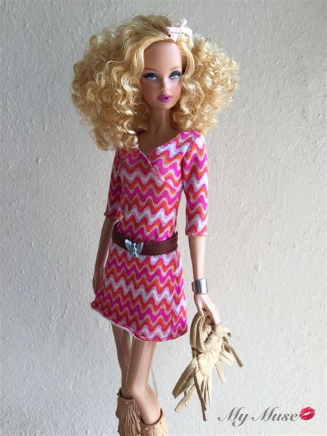 A Barbie Doll With Blonde Hair Wearing A Pink And White Chevron Dress Holding A Purse