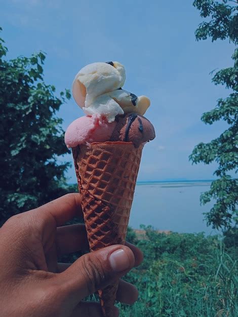 Premium Photo Cropped Hand Holding Ice Cream Cone Against Sky