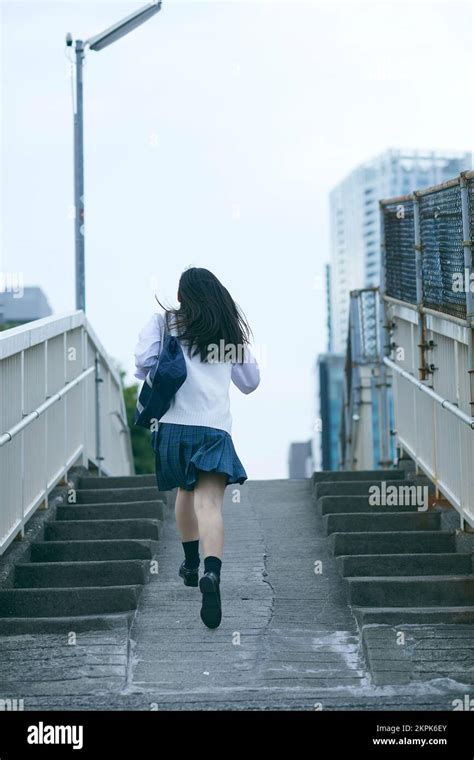 Japanese High School Girl Running On A Pedestrian Bridge Stock Photo