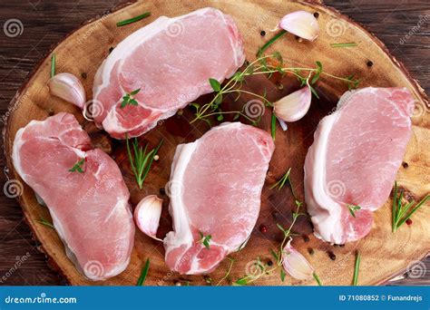 Raw Fresh Boneless Pork Chops With Herbs On Wooden Board Stock Photo