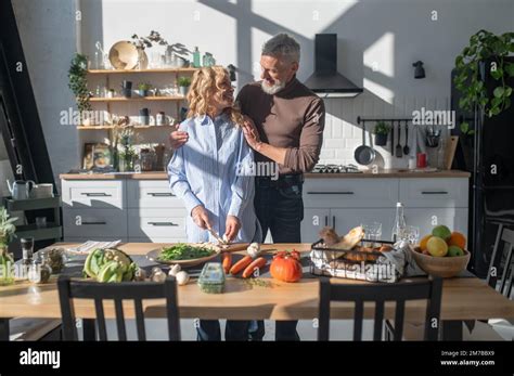 Mature Couple Cooking Together In The Kitchen And Looking Happy Stock