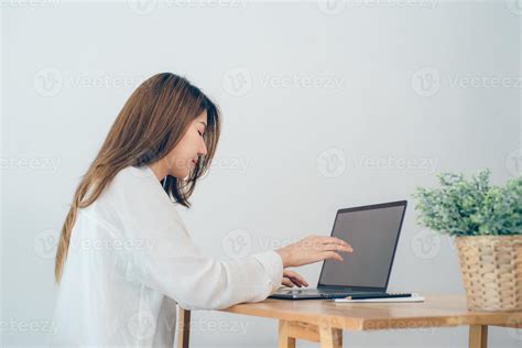 Beautiful Young Smiling Asian Woman Working On Laptop While Sitting In