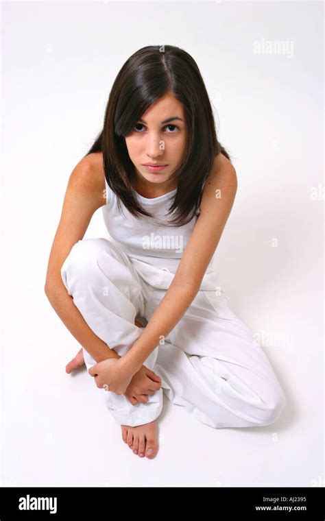 Young Black Haired Girl In White Shirt And Pants Sitting On The Floor