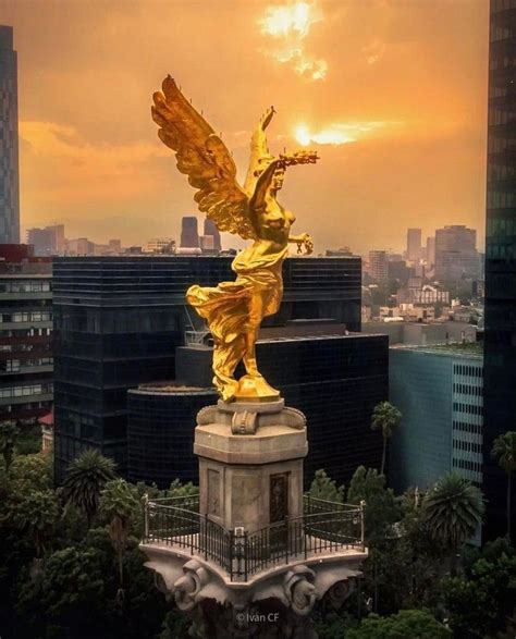 A Golden Angel Statue On Top Of A Building In The Middle Of A City At