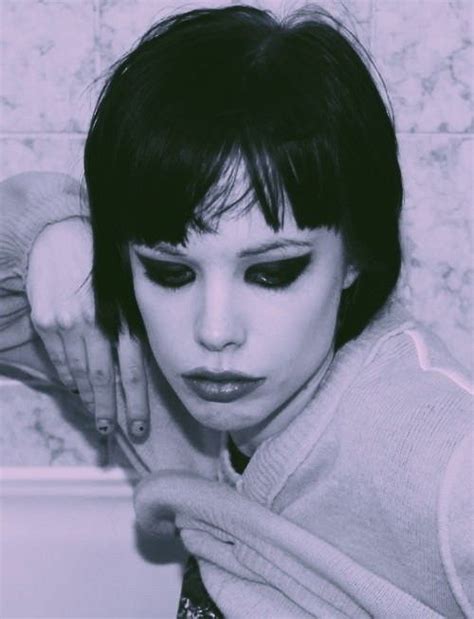 A Woman With Black Eyeliners Posing In Front Of A Bath Tub