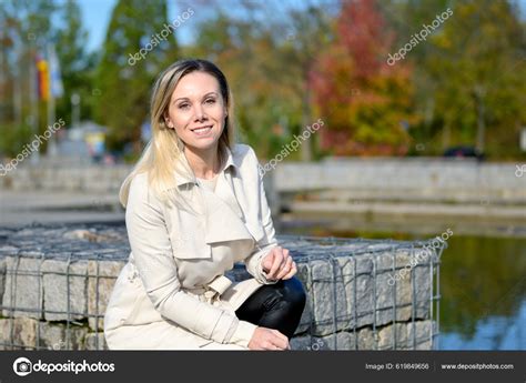 Attractive Middle Aged Blonde Woman Kneeling Lake Looking Camera Front