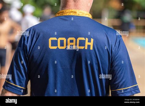 Back View Of Swimming Coaches Wearing Coach Shirt Working At An