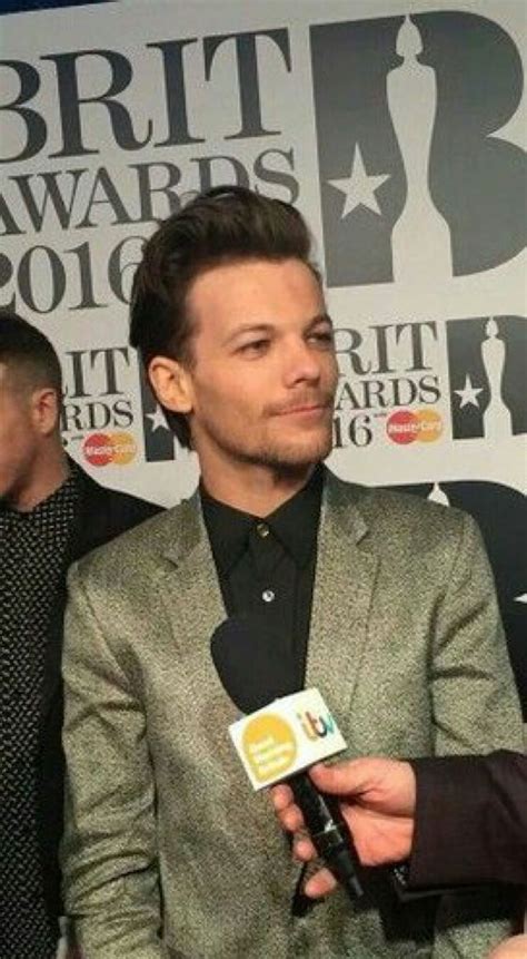 A Man In A Suit Talking To Someone On The Red Carpet At An Awards Event