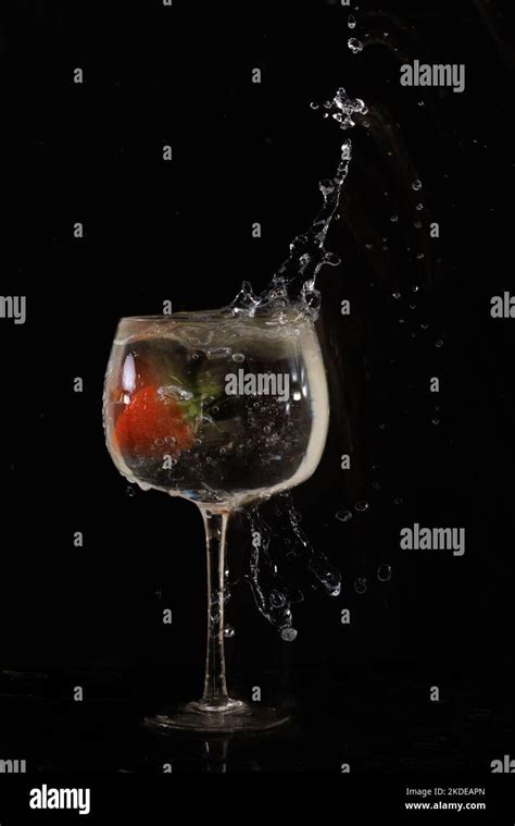 Strawberry Dropped Into Wine Glass Of Water With Splash On Black