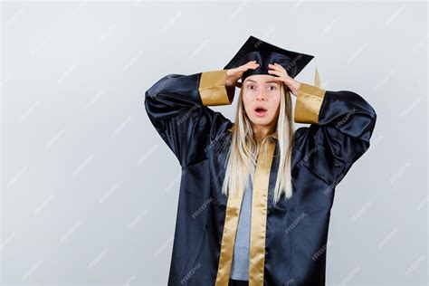 졸업 가운과 모자에 이마에 손을 잡고 놀 찾고 금발 소녀 무료 사진