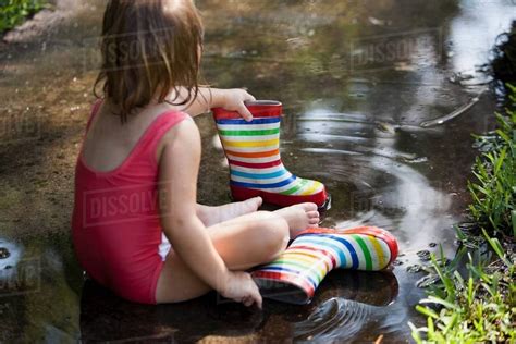 Child In Wellies Sitting In Puddle Of Water Stock Photo Dissolve