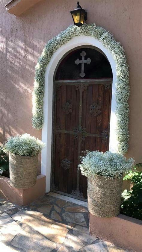 Two Potted Plants Are In Front Of A Door With A Cross On The Side